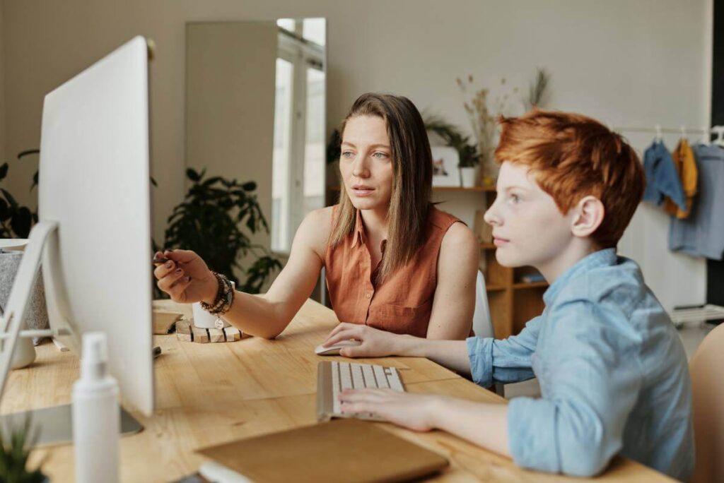 lady helping child to learn on online class