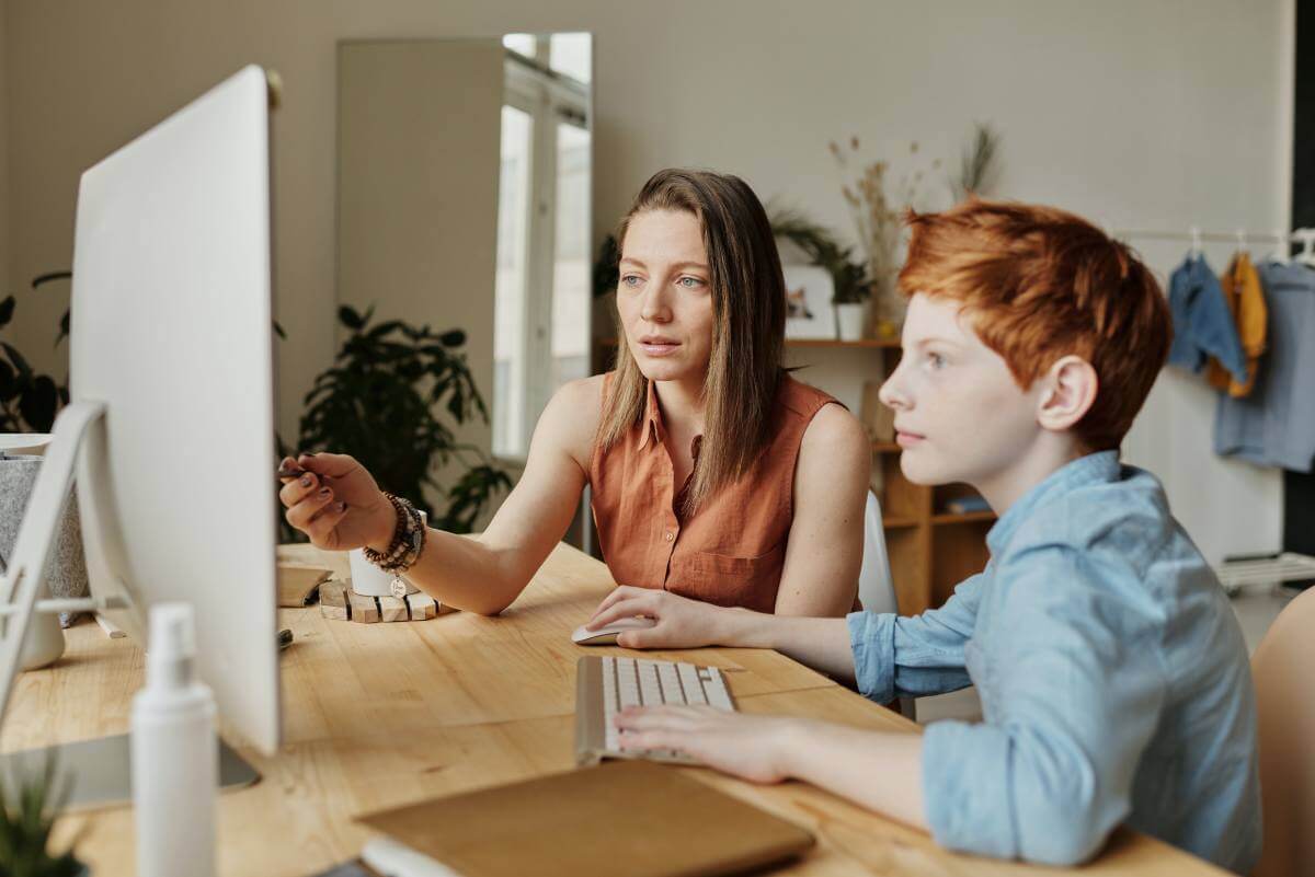 lady helping child to learn on online class