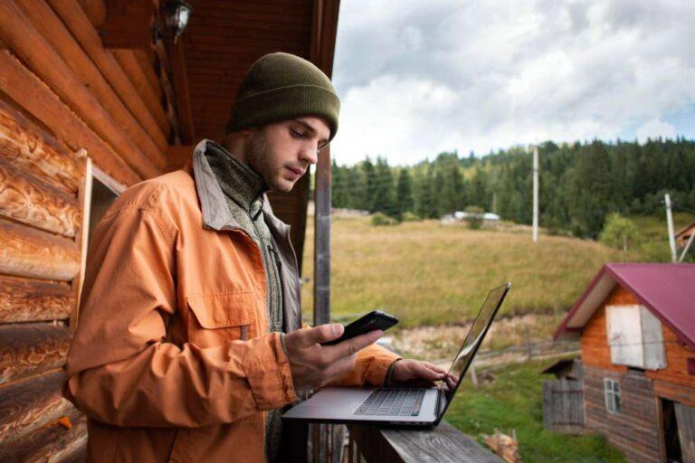 Guy using laptop holding phone in Rural areas